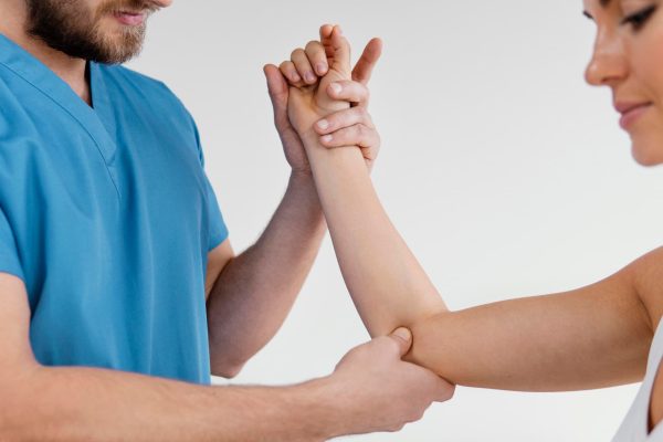 Therapist checking female patient elbow joint.