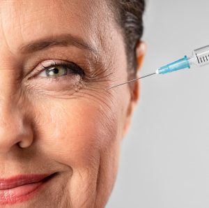 Smiley elder woman using injection for her eye wrinkles